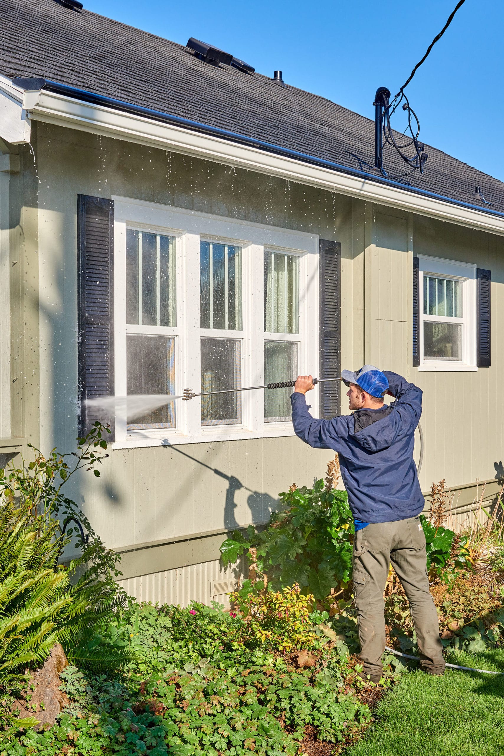 professional washing siding of brown home